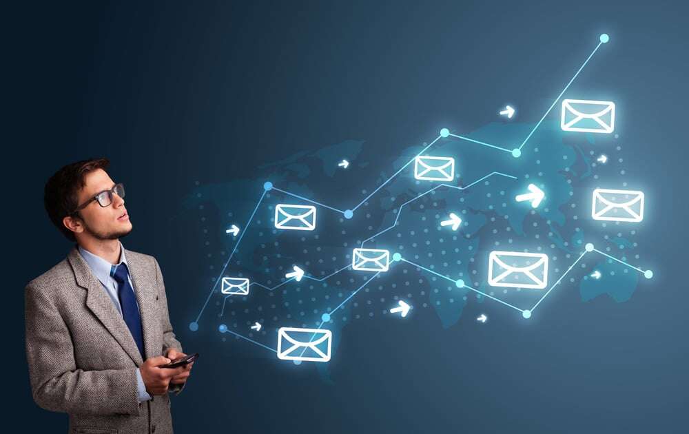 Attractive young man standing and holding a phone with arrows and message icons